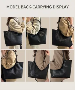 Detail view of the black woven leather tote bag texture and long shoulder strap design
