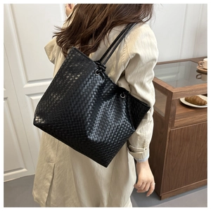 Detailed view of black woven tote bag with fine shoulder straps and textured finish