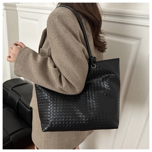 Detailed close-up of high-quality black woven leather tote bag with elegant silver hardware