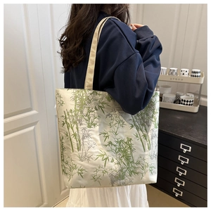 Detail of bamboo embroidery tote bag on shoulder showing wide strap and canvas texture