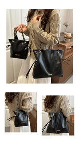 Detail of black leather bucket bag set with gold fashion hardware and chain straps