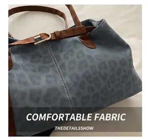 Detail of leopard print tote bag featuring brown faux leather strap and golden buckle