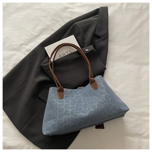 Detail of blue leopard print tote bag with brown straps on artistic white background