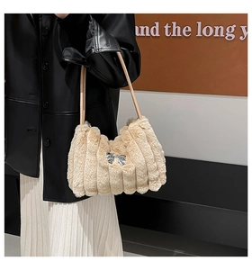 Vue détaillée du sac à épaule en peluche beige avec texture rayée et nœud métallique argenté