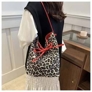 Detailed view of leopard print tote bag with orange straps and large bow on model