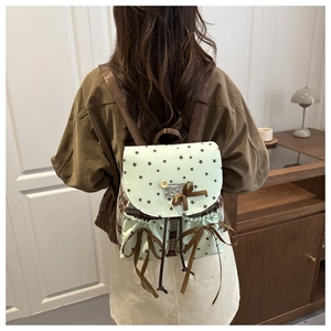 Mint green mini backpack with black star patterns and brown bow detail on model