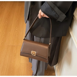 Detail of vintage brown leather baguette bag with a golden square twist-lock buckle