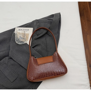 Flat lay of brown crocodile pattern underarm bag on a suit with artistic lifestyle props