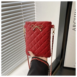 Close-up of a red quilted leather bag with a golden bow and elegant chain strap