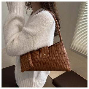 Detail of woven brown leather shoulder bag featuring a V-shaped pattern and gold buckle