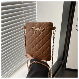 Close-up of brown quilted phone bag with a golden bow and chain strap being held