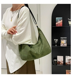 Detail of dark green suede hobo bag with contrast stitching and golden zipper on shoulder