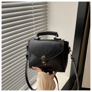 Gros plan d'un mini sac bandoulière vintage en cuir noir avec fermoir métallique et poignée