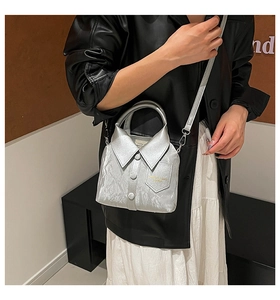 Detailed view of silver shirt-shaped crossbody bag with pleated texture and button accents