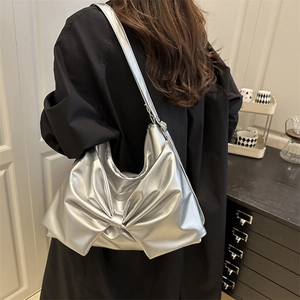 Silver metallic shoulder bag with large bow design and wide strap for casual wear