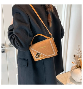 Detail view of brown crossbody bag with contrast stitching and metal chain lock buckle