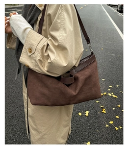 Brown matte tote bag with leather strap worn by a model in a city autumn setting