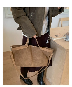 Detail view of large brown suede tote bag with leather piping and adjustable shoulder strap