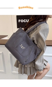 Détail du sac fourre-tout en nylon gris foncé avec broderie TGT et bandoulière