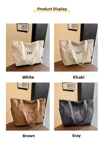 Détail de sacs fourre-tout en toile quatre couleurs avec broderie TGT sur table en bois