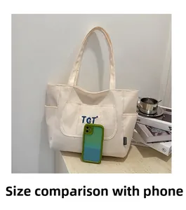 Détail du sac fourre-tout en toile avec broderie TGT et intérieur spacieux pour mobile