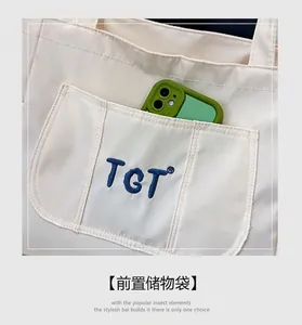 Détail du sac fourre-tout en toile avec poche avant et broderie TGT élégante