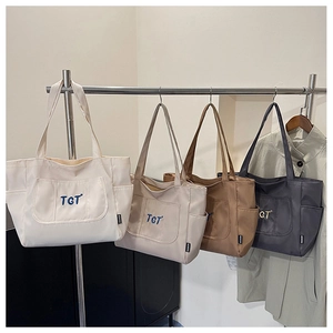 Détail de quatre sacs fourre-tout en toile avec broderie TGT en blanc, beige, marron et gris