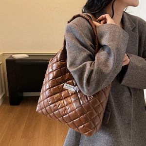 Borsa tote trapuntata marrone di grande capacità con finitura lucida su modella