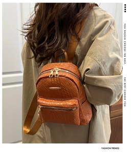 Detail of woven texture on brown PU leather backpack with gold zipper and stylish straps
