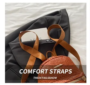 Detail view of brown woven texture backpack with wide shoulder strap and gold zipper