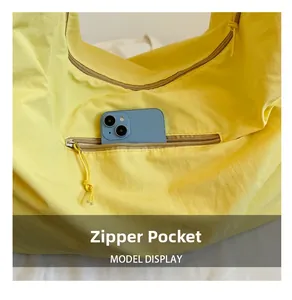 Detail der gelben Nylon-Schultertasche mit funktionalem Reißverschlussfach und Handy