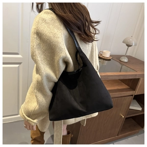 Side view of a black oversized hobo bag in matte finish styled on model shoulder