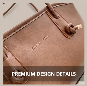Detail view of brown leather tote with embossed logo and knotted strap with gold metal ends