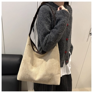 Close-up of a large beige suede tote bag with brown leather strap on person