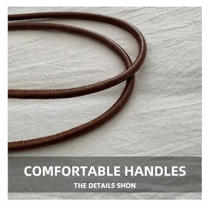Detailed macro view of dark brown leather handles with precise stitching on a tote bag
