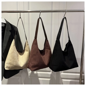 Close-up of minimalist suede tote bags in beige brown and black hanging on a metal rack