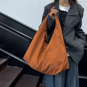 Minimalistische große Schultertasche in Karamell an einem Model im urbanen Stil