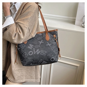 Detail of large tote bag with HORHE monogram pattern and brown leather straps on model