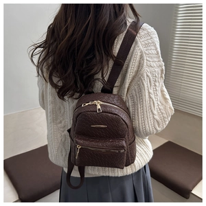 Detailed view of woven texture on mini brown backpack with gold zipper accents