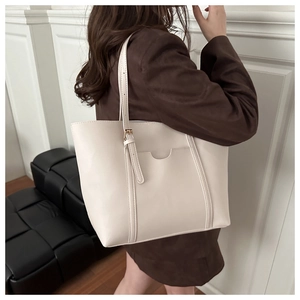 Detail view of large cream tote bag with adjustable straps and front pocket detail