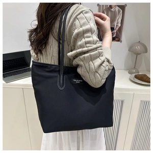 Seitenansicht einer großen schwarzen Nylon-Tragetasche an einem Modell in Minimal-Stil