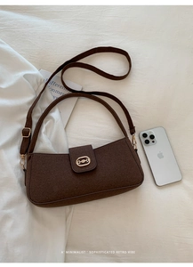 Brown wool shoulder bag with gold metal buckle and adjustable strap on a white fabric surface