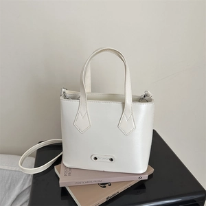 Detalle de bolso tipo cubo en cuero PU blanco con logo metálico FASHION y correa extraíble