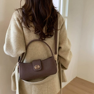 Retro matte dark brown crossbody bag with gold buckle on beige wool coat model
