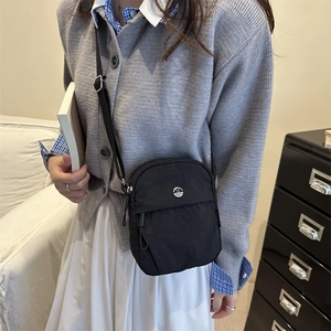 Minimalist black nylon crossbody bag with metal M logo and adjustable strap for women