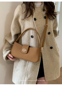 Detail of vintage brown suede shoulder bag featuring a gold horsebit buckle and slim strap