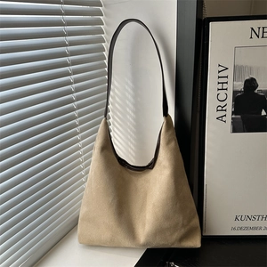 Minimalist beige suede hobo tote bag with dark brown leather straps in soft natural light