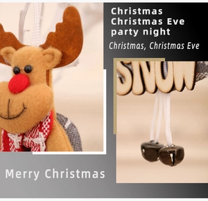 Detail of plush reindeer ornament with SNOW wooden sign and metal bells for Christmas tree