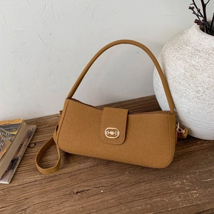 Vintage caramel suede shoulder bag with gold metal buckle on a rustic wooden table