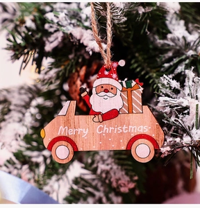 Detailed view of a red wooden car ornament with Santa Claus hanging on a snowy Christmas tree